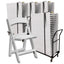 White folding chair next to a stack of white chairs on a black cart against a white background