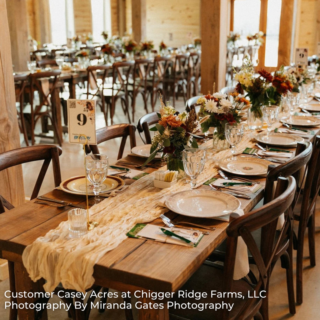 Dining hall with long wooden tables set for a meal, featuring floral centerpieces and place settings.